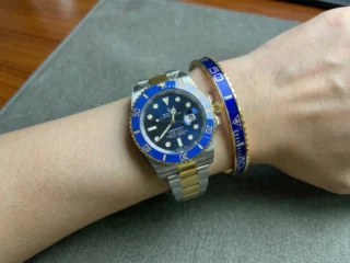 Close-up of a wrist wearing a sleek Blue Submariner Gold Tone Bracelet perfectly paired with a Submariner watch.