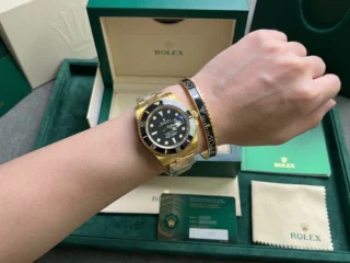 Close-up of a wrist wearing a sleek Black Submariner Gold Tone Bracelet perfectly paired with a Submariner watch.